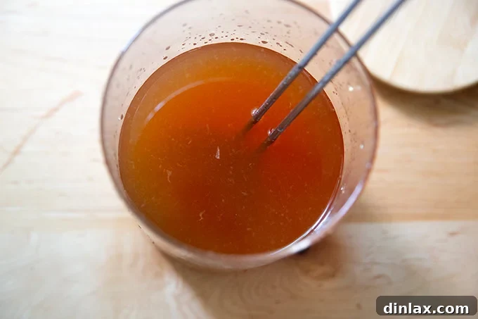 A large glass vessel filled with iced tea, featuring a ladle resting inside, ready for serving.