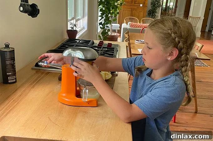 A young girl, Tig, happily juicing lemons into a bowl, demonstrating a hands-on step in making iced tea.