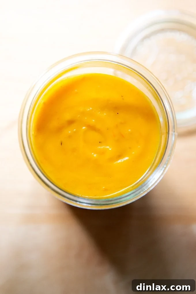 A beautifully sealed jar of golden roasted yellow tomato sauce, reflecting light and promising fresh, summery flavors.