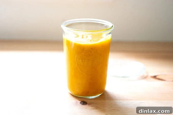 A beautifully clear glass jar filled with the freshly made, bright golden roasted yellow tomato sauce, sealed and ready for storage or immediate use.