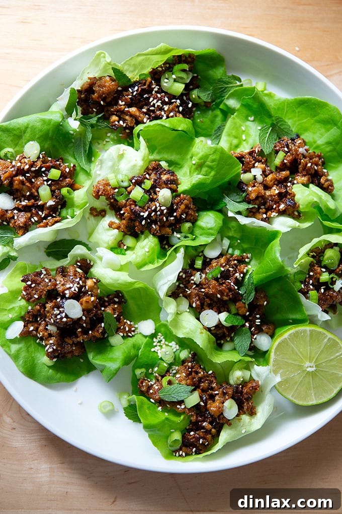 A beautifully arranged plate of crispy miso-lime tofu crumbles nestled in fresh lettuce cups, garnished with sesame seeds and scallions.
