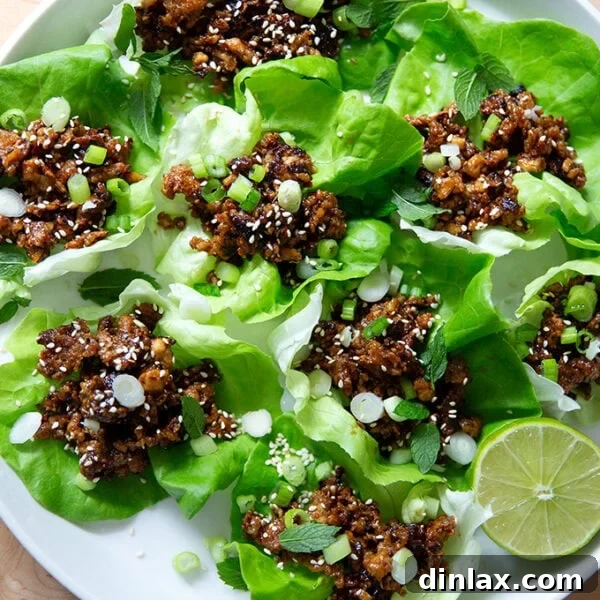 A plate of crispy miso-lime tofu crumbles served in fresh lettuce cups, garnished with herbs and sesame seeds.