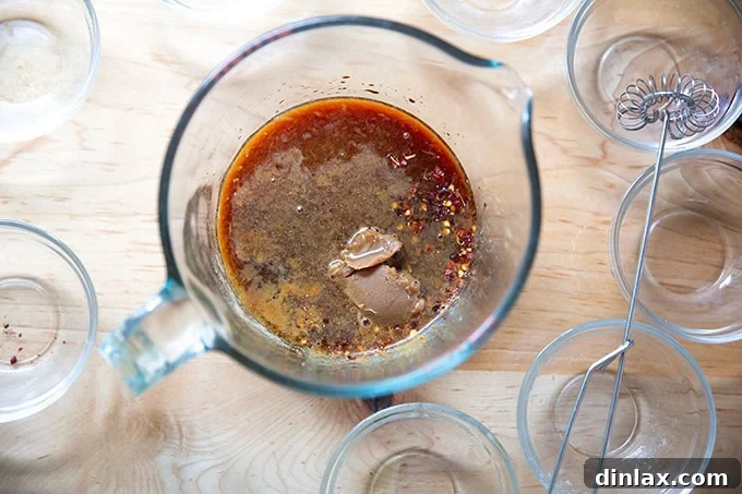 A 4-cup measuring cup containing the unwhisked ingredients for the miso-lime sauce, showcasing the distinct components before blending.