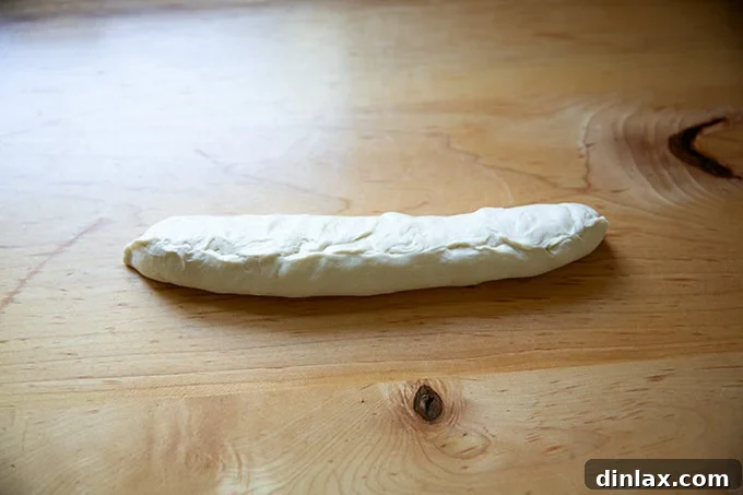 A fully shaped, unbaked baguette, with the seam down, ready for proofing.