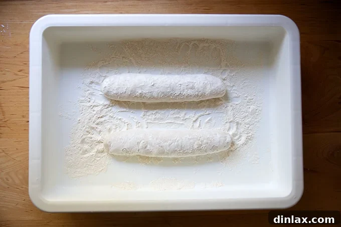 Two unbaked baguettes, slightly separated, proofing within a DoughMate container.