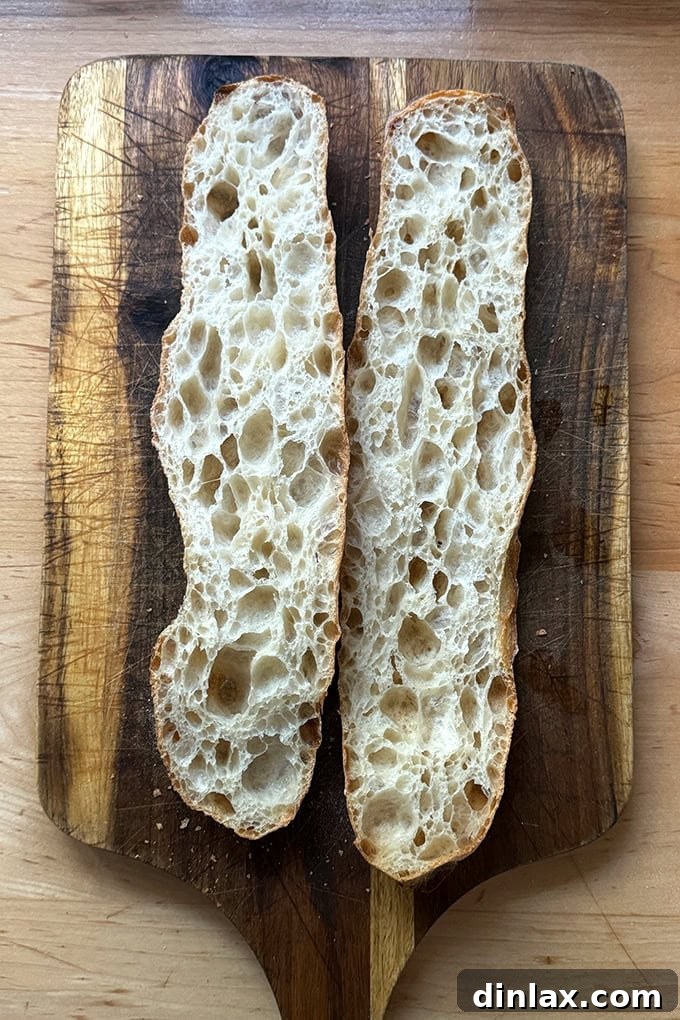 A halved open-crumb baguette made without refrigeration, showcasing its airy interior.