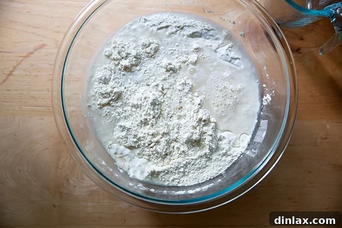 Cold water poured into a bowl containing the mixed dry ingredients for baguette dough.