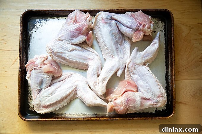 Make Ahead Roasted Turkey Wing Stock 4 Fresh turkey wings arranged neatly on a sheet pan, ready for roasting.