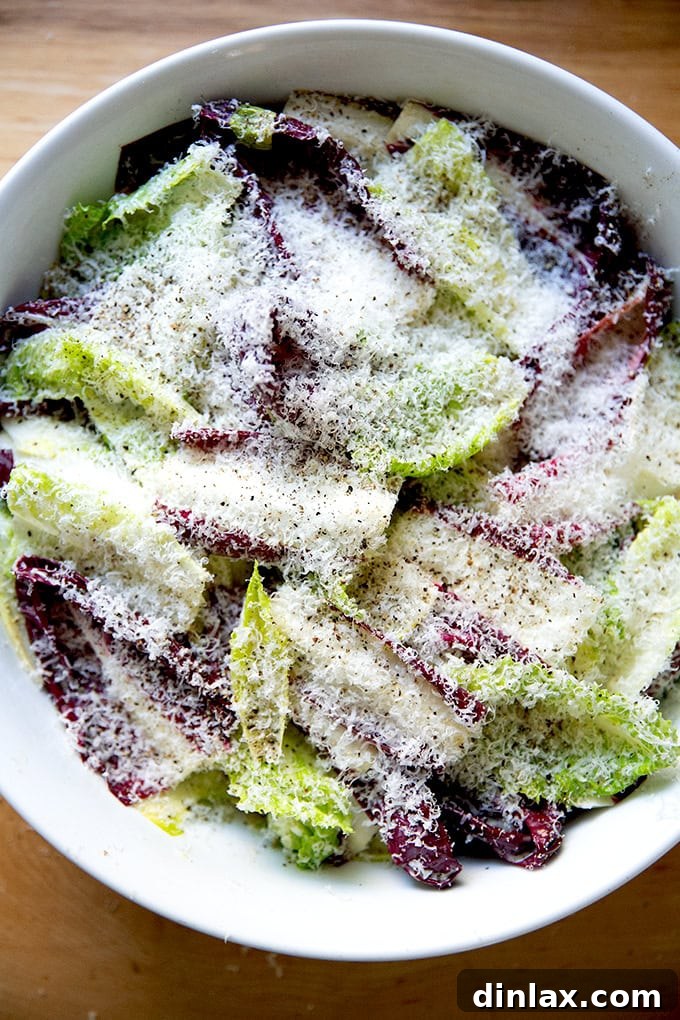 Perfect Caesar Dressing Your Way 17 A close-up view of a Caesar salad bowl, fully garnished with grated Parmesan and freshly cracked black pepper.