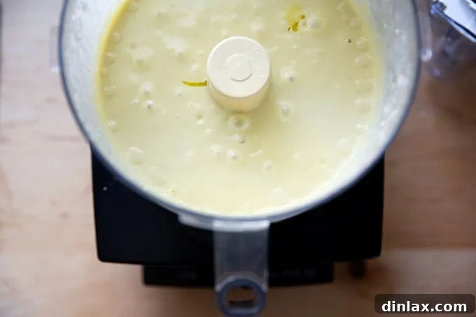 Perfect Caesar Dressing Your Way 9 A close-up of thick, creamy Caesar dressing inside a food processor bowl, having reached its final emulsified state.
