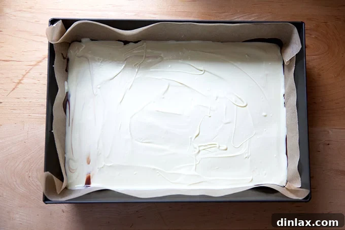 Simple 4-Ingredient Peppermint Bark 13 A layer of melted white chocolate spread over a layer of dark chocolate in a 10x14-inch pan.