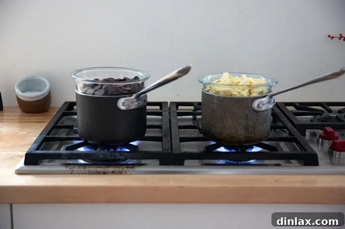 Simple 4-Ingredient Peppermint Bark 7 Two pots holding two bowls of chocolate set over boiling water.