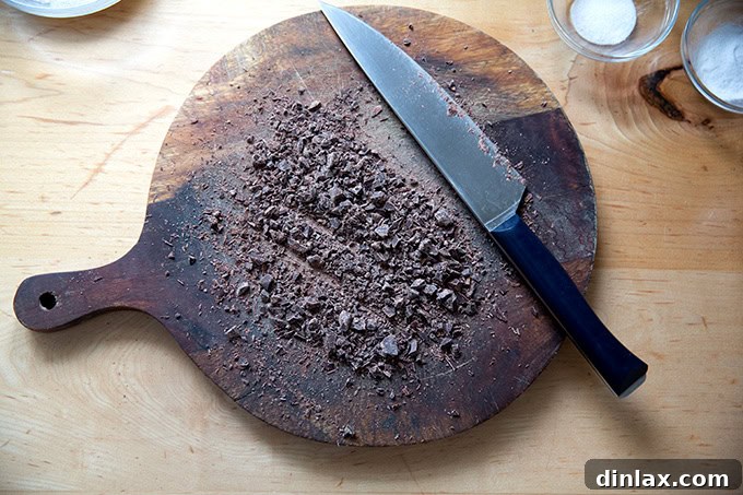 Finely chopped bittersweet chocolate on a cutting board, ready to be added to the dough.