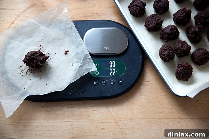 Portioned chocolate crinkle cookie dough balls on a digital scale, ensuring precise measurements.