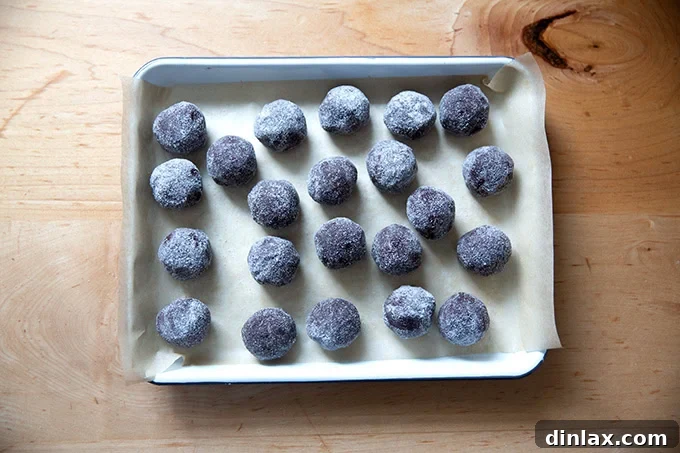 Chocolate crinkle cookie dough balls, coated in granulated sugar, on a small tray before freezing.