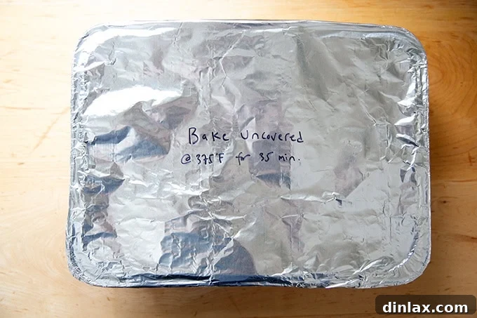 Effortless Baked Pasta: Make It, Share It, Freeze It 20 An unbaked pasta dish in a foil pan, covered with foil, featuring handwritten baking instructions on top.