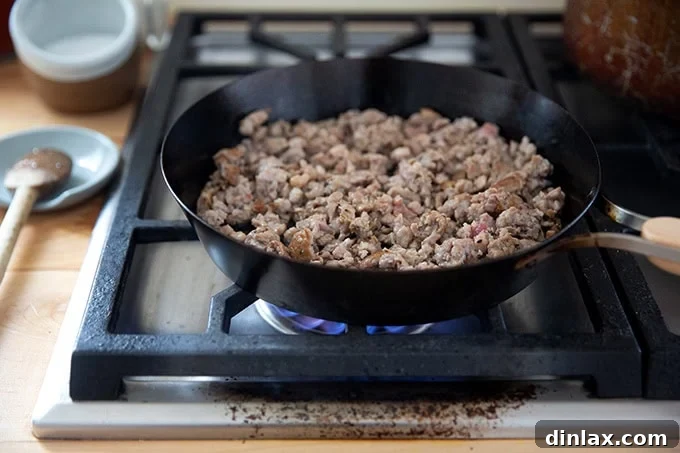 Effortless Baked Pasta: Make It, Share It, Freeze It 8 A skillet filled with browning sausage crumbles on a stovetop.