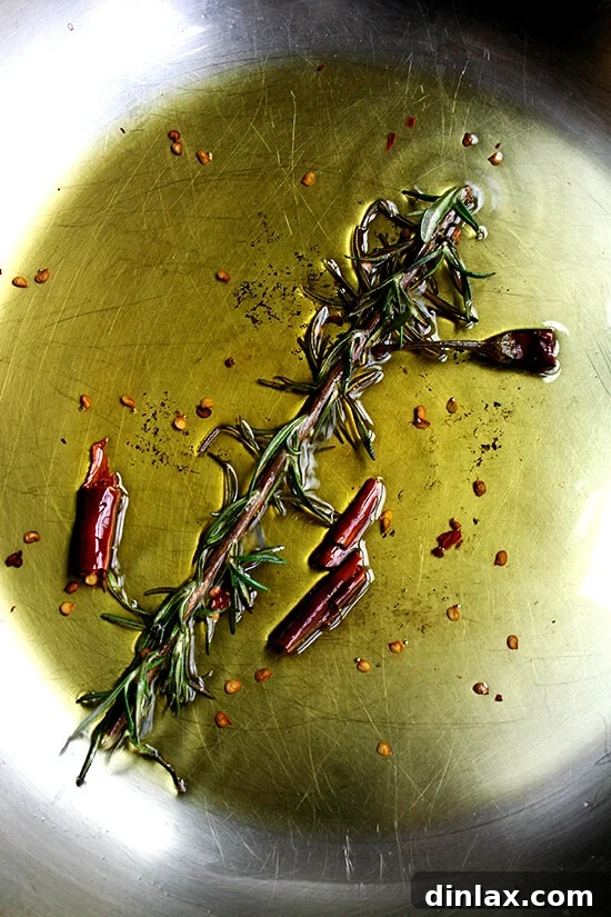 Rosemary and Chile de Árbol Sizzling in Olive Oil Fresh rosemary sprig and dried chile de árbol sizzling gently in olive oil.
