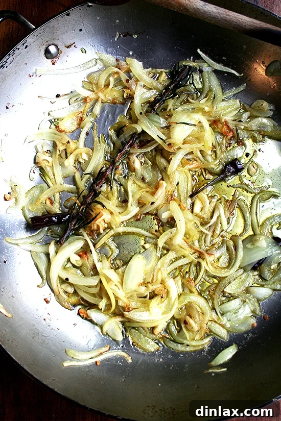 Onions Beginning to Brown for Flavor Base Sliced yellow onions softening and caramelizing in a pan.