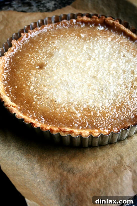 The exquisite texture of this maple cream tart is truly remarkable, offering a smooth, creamy experience without eggs, reminiscent of a perfect crème brûlée. A delight for any maple syrup enthusiast, and surprisingly simple to prepare. Just-baked maple cream tart on a sheet pan, ready to be enjoyed.