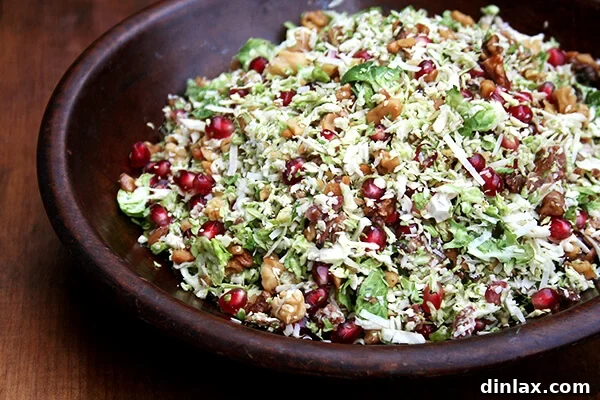 A vibrant salad featuring shaved Brussels sprouts, crispy bacon, and bright pomegranate seeds.