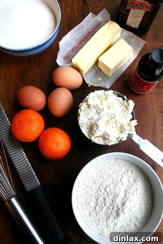 A selection of fresh ingredients, including oranges, ricotta cheese, butter, and flour, laid out for baking an orange-ricotta loaf.