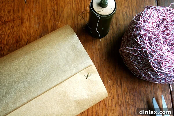 A close-up shot of parchment paper being sewn, suggesting careful preparation for packaging and gifting the baked loaves.