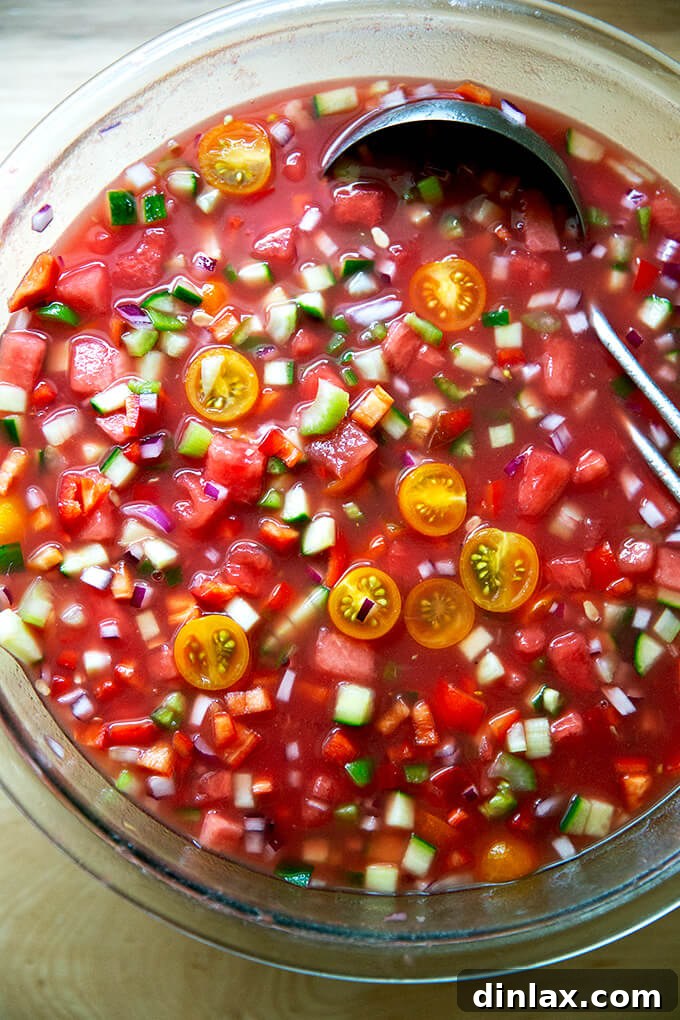 A large glass bowl filled with freshly mixed watermelon gazpacho, chilling before serving.