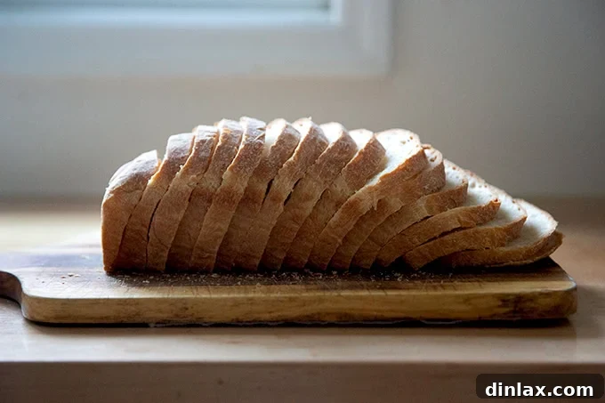 Pillowy Soft No Knead Sandwich Loaf 20 A beautifully sliced loaf of soft sandwich bread, presented on a wooden cutting board.