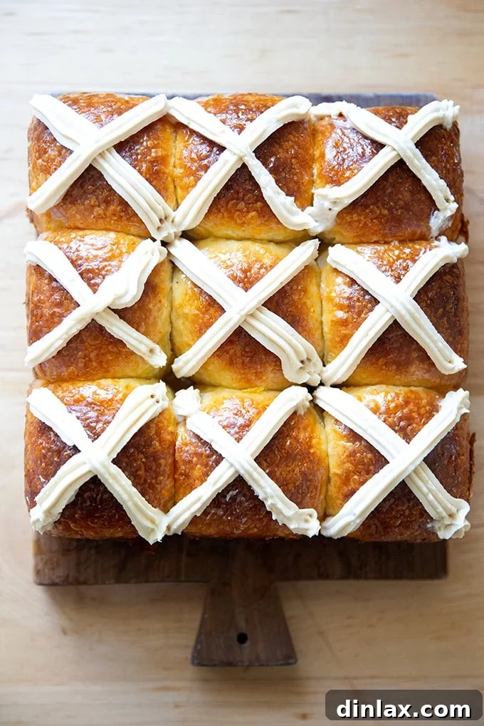 Nine perfectly baked hot cross buns arranged on a rustic wooden serving board, ready to be enjoyed as a delightful Easter treat.