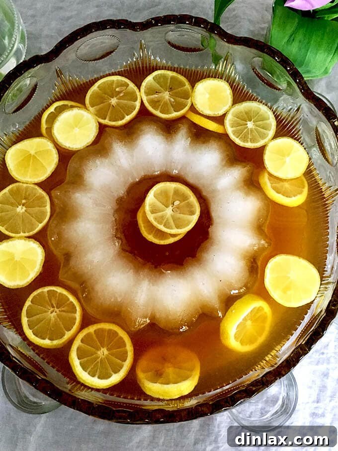 A large glass punch bowl filled with Philadelphia Fish House Punch, garnished with lemon slices and ice, ready for serving.