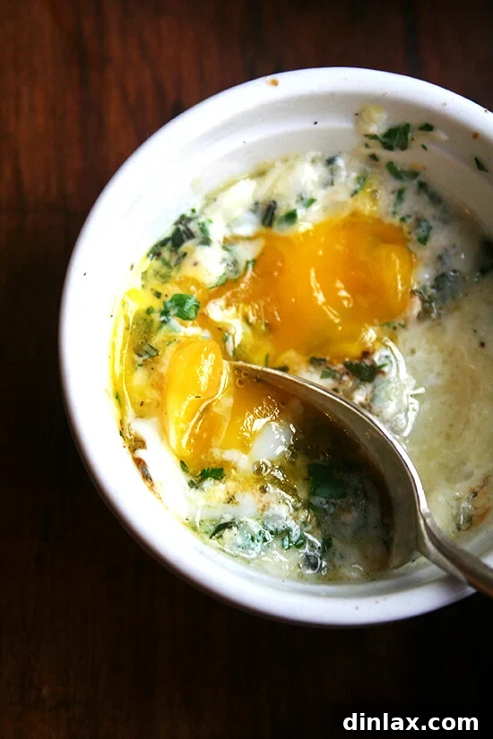 A ramekin holding a baked (shirred egg) with a spoon.