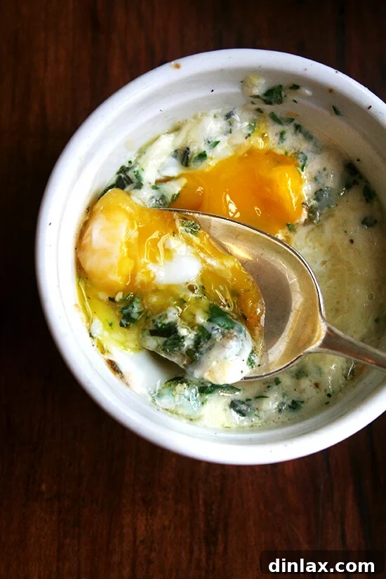 A ramekin holding a baked (shirred egg) with a spoon.