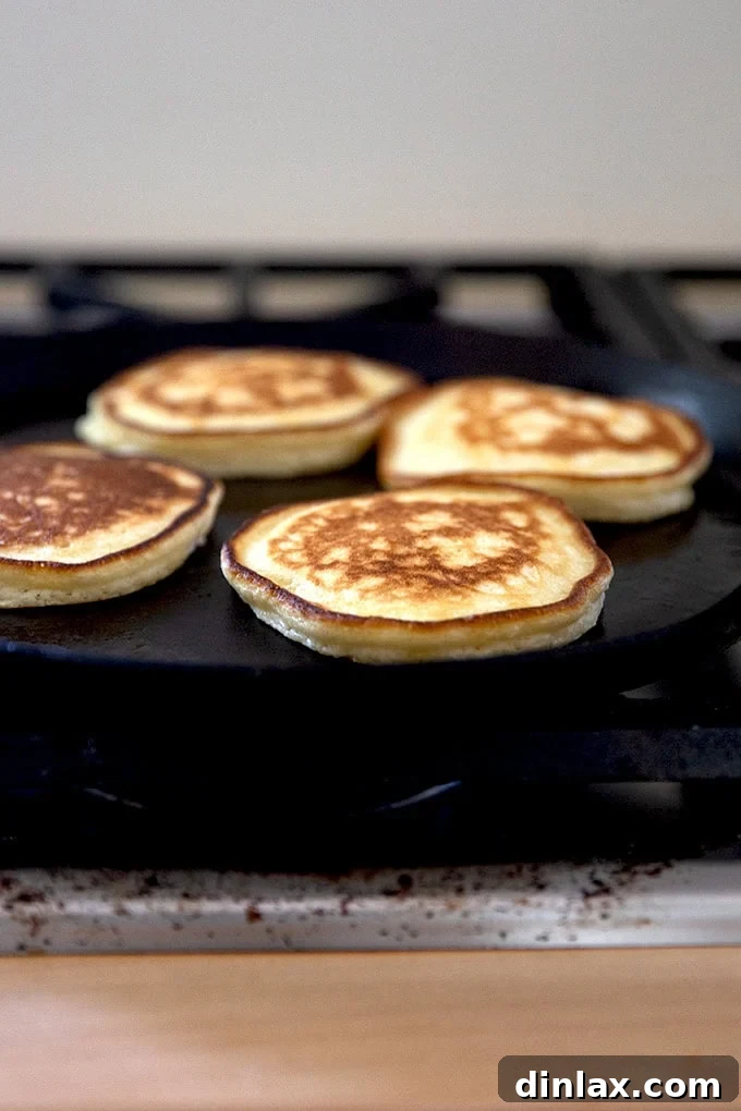 Quick Light and Fluffy Sourdough Discard Pancakes 13 Sourdough discard pancakes cooking in a skillet.