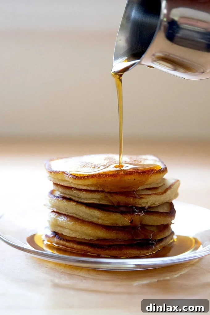 Quick Light and Fluffy Sourdough Discard Pancakes 16 A stack of sourdough discard pancakes on a plate being drizzled with syrup.