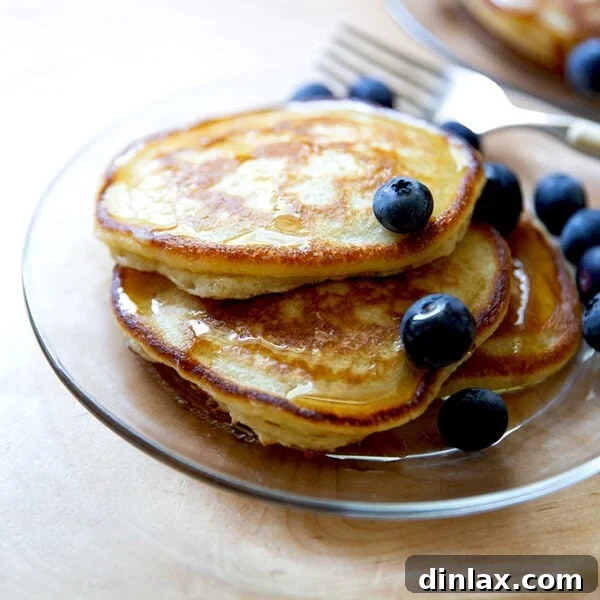 A plate of sourdough discard pancakes topped with syrup and blueberries.
