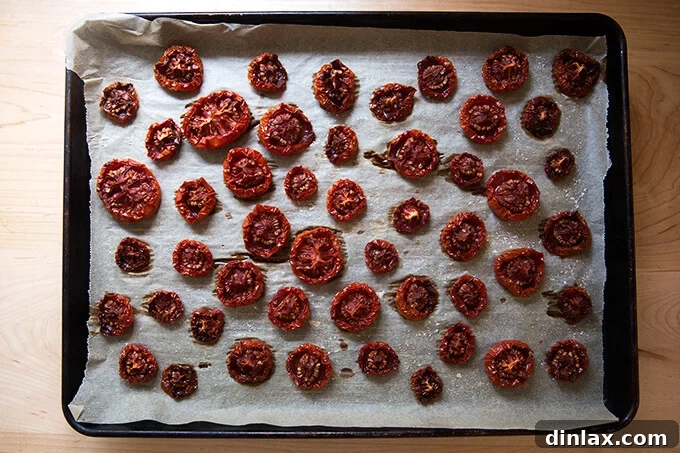 Oven-Dried Tomatoes and Delectable Toasts 6 Oven-dried tomatoes on a parchment-lined sheet pan, close up