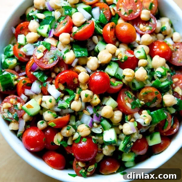 A large bowl of vibrant, lemony herby chickpea salad, garnished and ready to be served, showcasing its fresh ingredients.