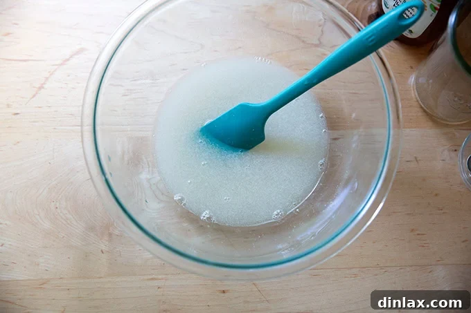 The mixture of water, salt, honey, and yeast, thoroughly stirred together in a large bowl, ready for the next step.