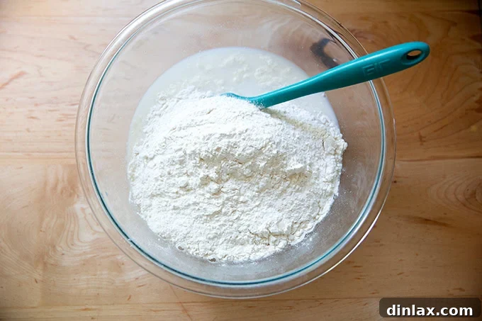 A large bowl filled with the liquid mixture, now with flour added on top, awaiting its initial mix.