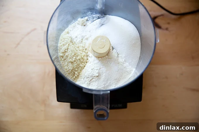 A food processor bowl filled with the combined dry ingredients for the crisp topping, ready for processing.