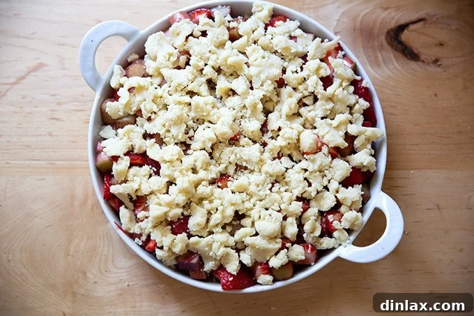 An unbaked strawberry-rhubarb crisp with the crumbly topping evenly spread over the vibrant fruit filling.