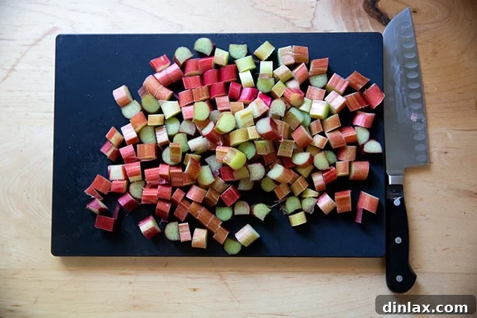 A cutting board displaying neatly sliced rhubarb pieces, uniform in size and ready for the bowl.