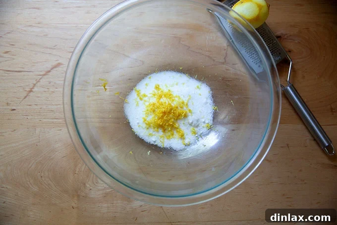 A large bowl containing 1/2 cup of sugar with fresh lemon zest delicately piled on top.