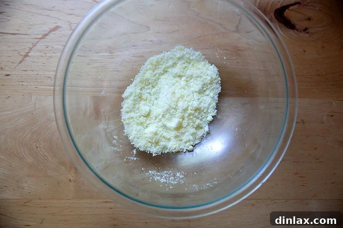 A bowl of sugar with lemon zest thoroughly rubbed into it, appearing fragrant and slightly moist.