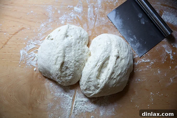Grandma-style pizza dough, neatly split into two evenly sized portions, resting on a clean countertop, awaiting shaping.