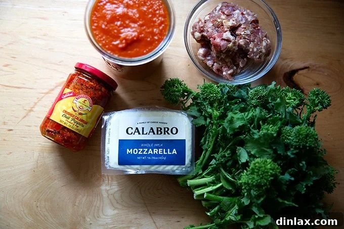 A vibrant selection of topping ingredients for a Grandma-style pizza, including fresh broccoli rabe, savory sausage, grated mozzarella, and a bowl of spicy tomato sauce, all neatly arranged on a countertop.