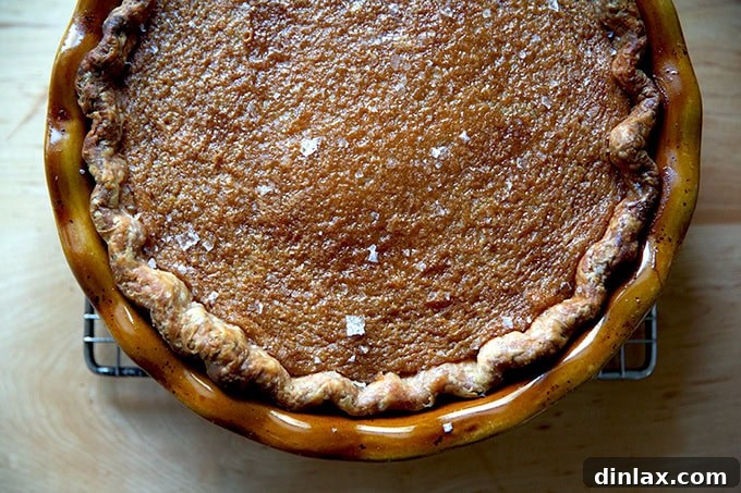 A stunning, freshly baked salted maple pie, with its rich caramelized top, ready to be sliced and served as a holiday dessert.
