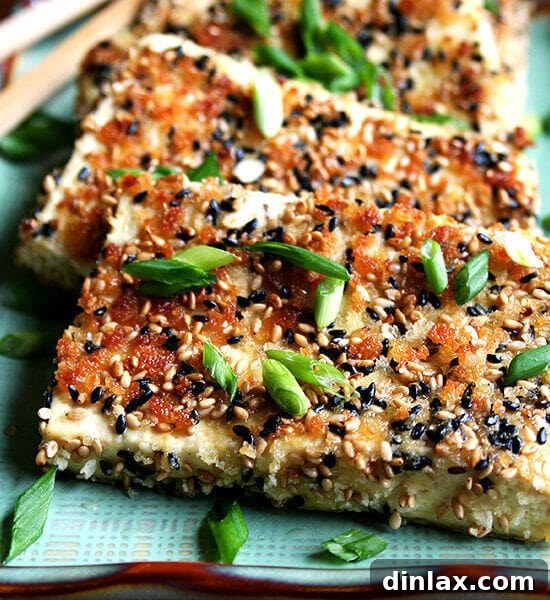 Crispy sesame-crusted tofu served on a platter with a side of nuoc cham sauce.