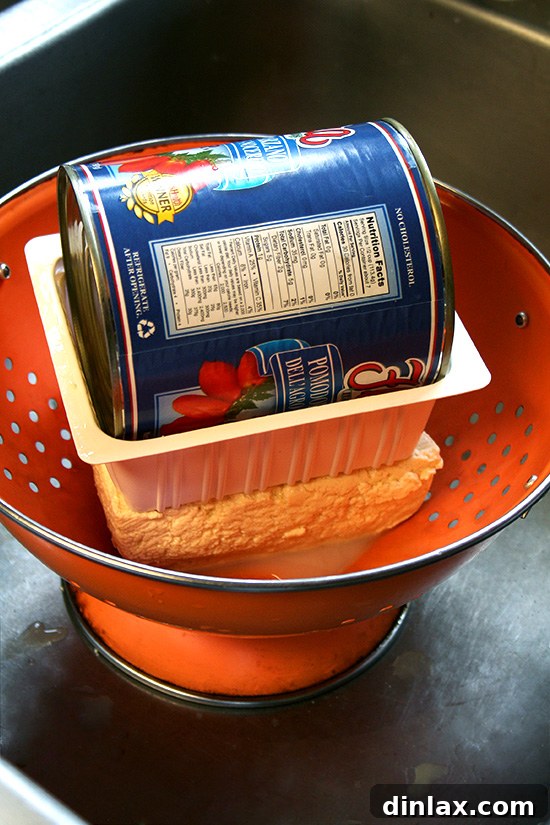 Golden Sesame Tofu with Tangy Nuoc Cham Drizzle 8 Draining excess water from tofu in a colander, weighted down to ensure crispiness.